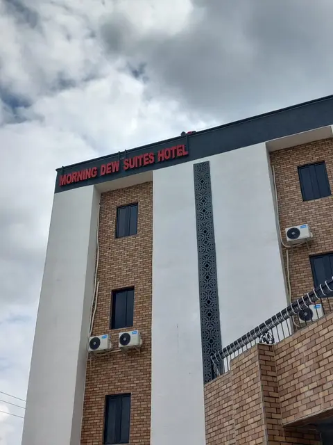 Red channel letters spelling Morning Dew Suites Hotel across the top fascia of the hotel in Owerri